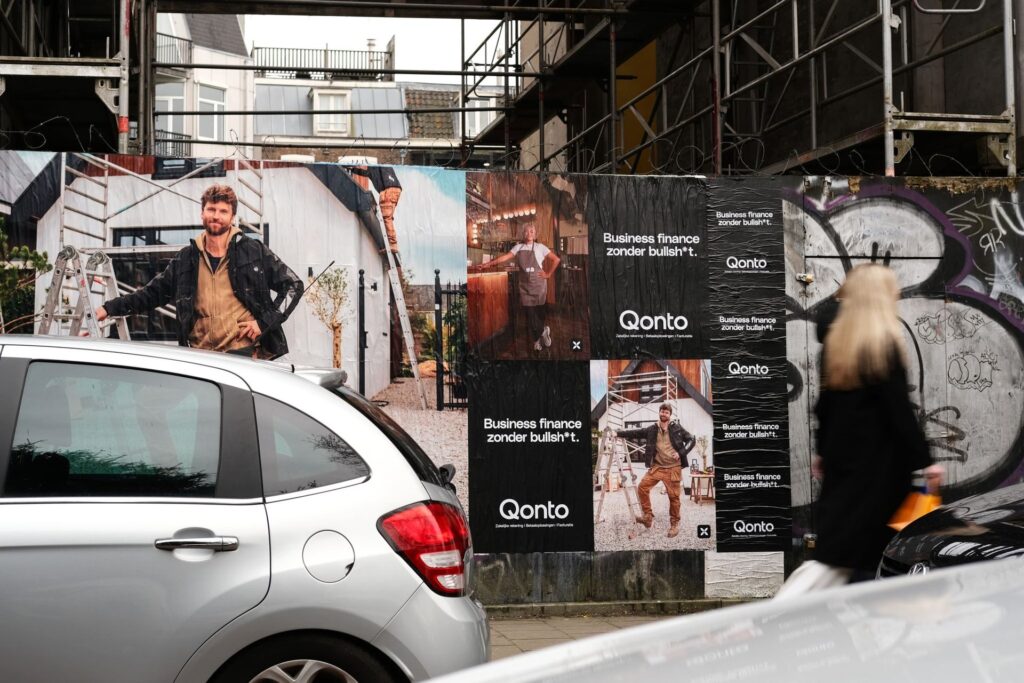 Bouwhek volgeplakt met Qonto-posters van echte ondernemers