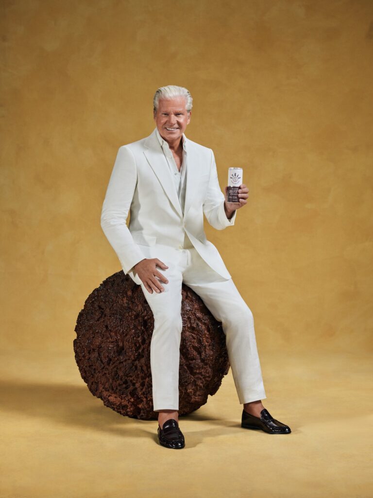Dries Roelvink in a white suit sitting on a giant meatball with a STELZ can in the Battle of Flavours campaign by Wolfstreet