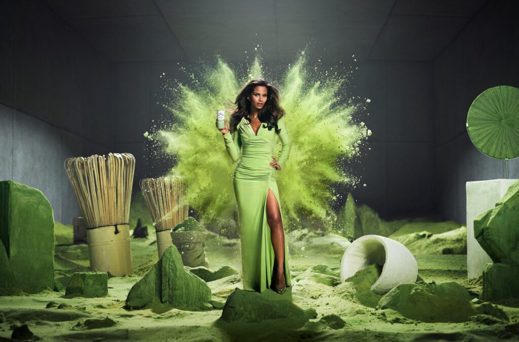 Model in a green dress in a matcha powder landscape with bamboo whisks for the STELZ Battle of Flavours campaign by Wolfstreet